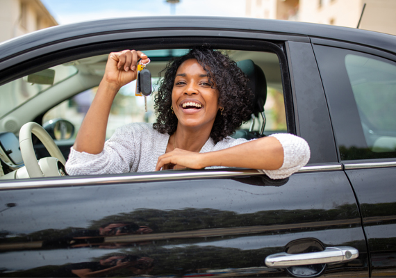 Young woman in car showing keys